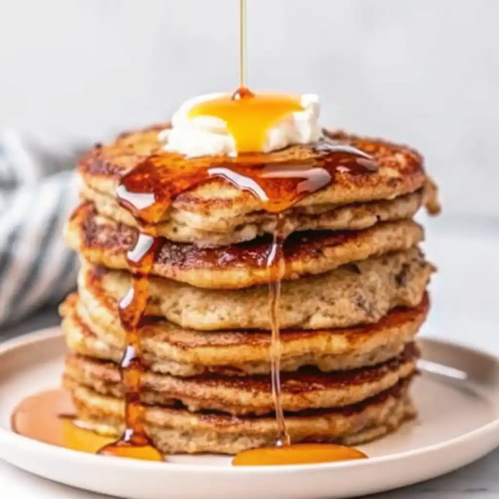 Stack of fluffy gluten-free almond flour banana pancakes topped with fresh berries and maple syrup
